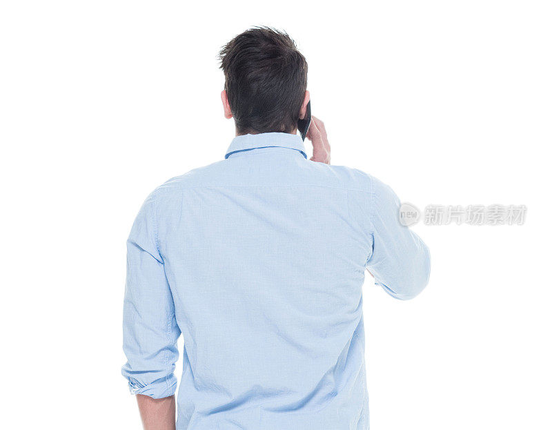 一个男人/一个人/腰部以上/ 20-29岁的成年英俊的人白人男性/年轻男子站着穿衬衫/衬衫谁在说话/冷静的态度和拿着手机/使用智能手机